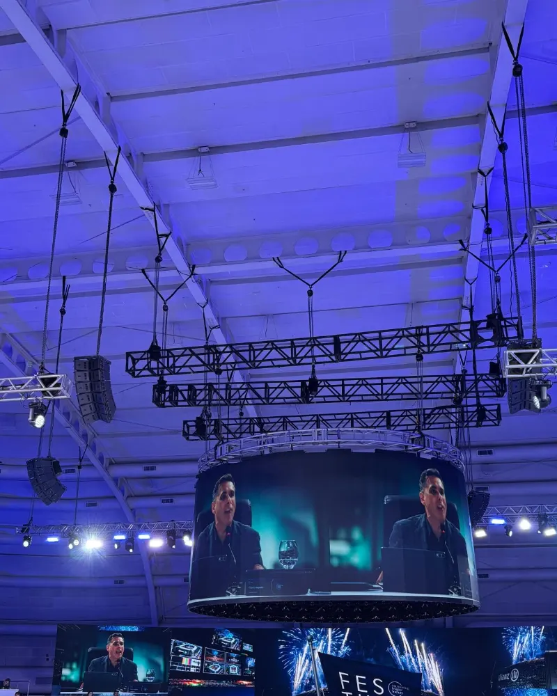 Arena com telão circular sobre o palco e plateia em evento corporativo